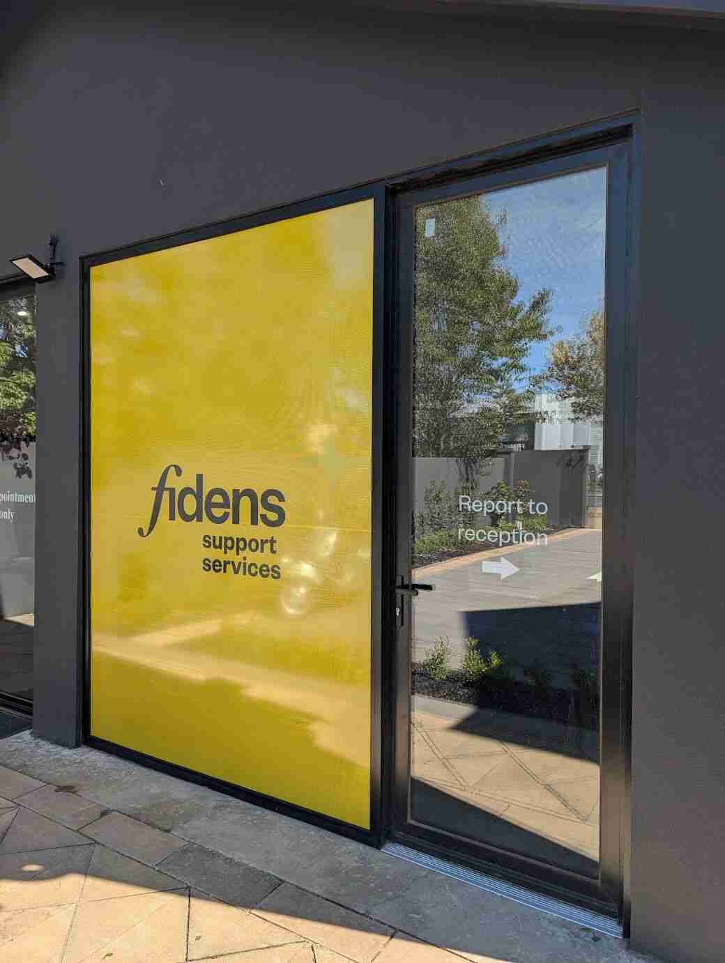 Fidens window signage with white logo on bright yellow branded panel