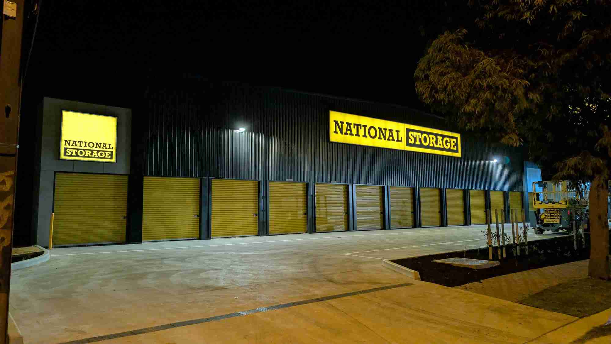 illuminated light box signs glowing evenly on a storage facility at night - gigantic signs adelaide