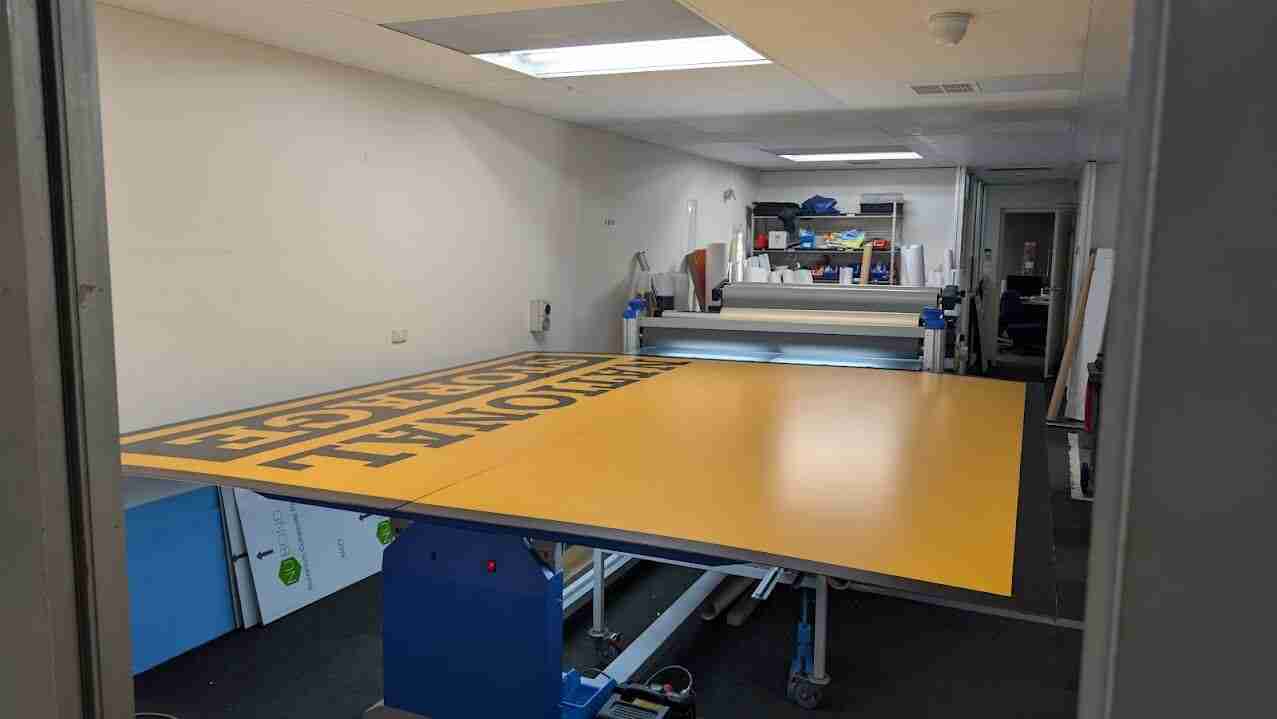 Large-format print production table inside commercial signage workshop