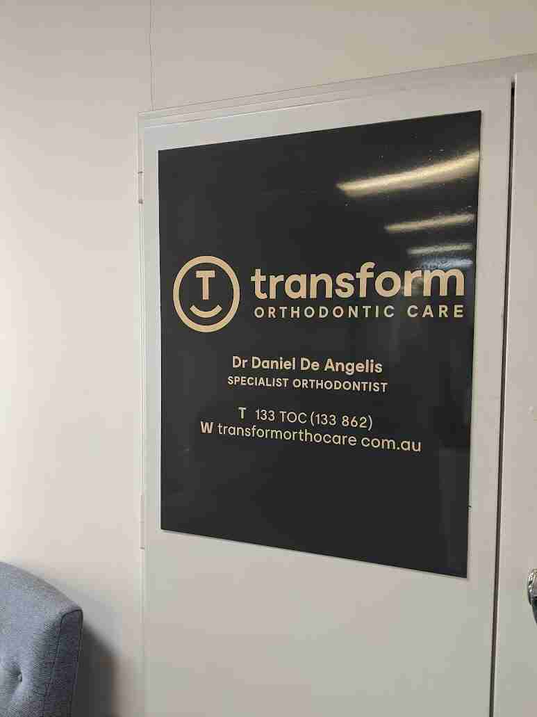 Transform black wall sign with gold logo and clinic details