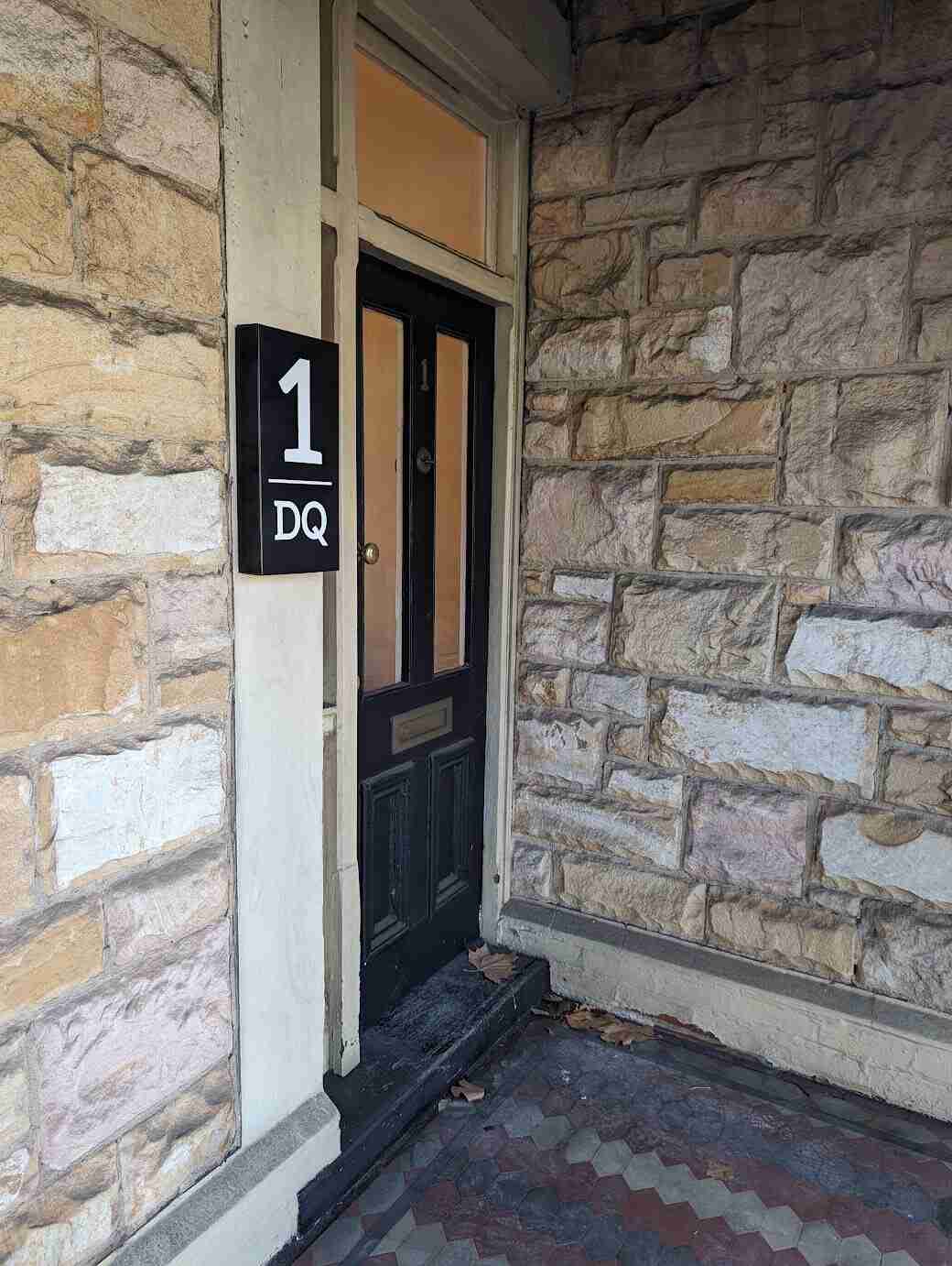 Black and white 1DO door number sign mounted on stone entry wall