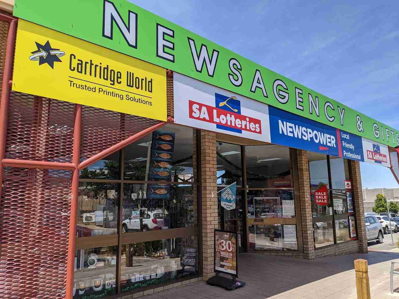 Newsagency storefront with green fascia signage and window graphics