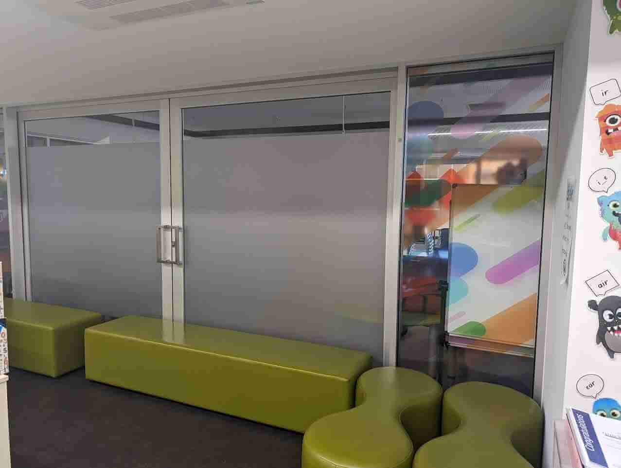 Frosted privacy film installed in modern office breakout area with seating