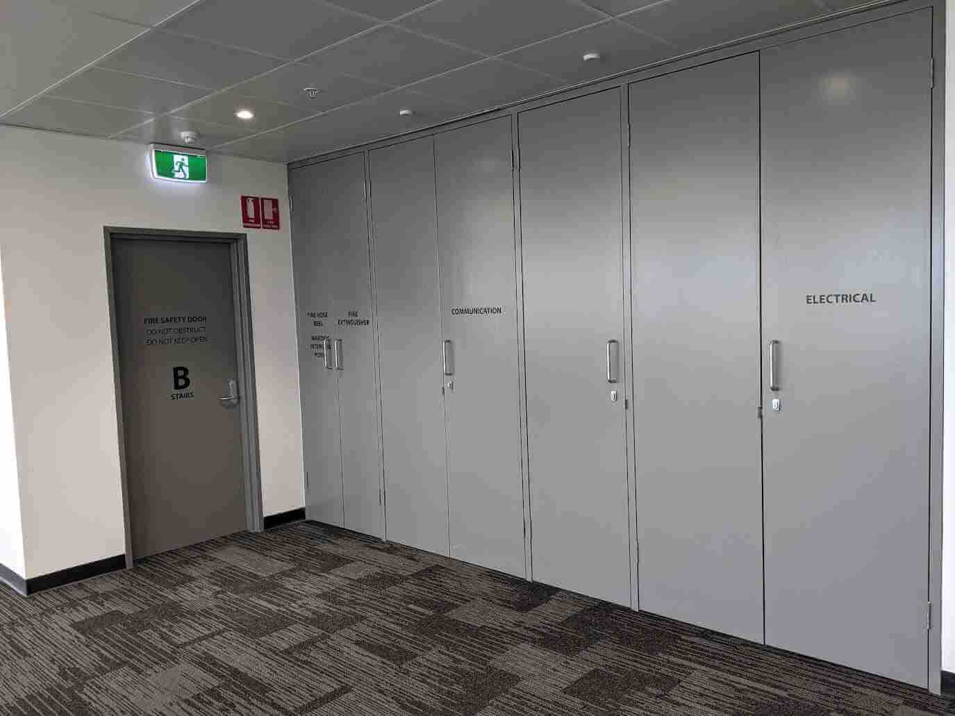 White built-in cupboard doors in office hallway with subtle signage elements