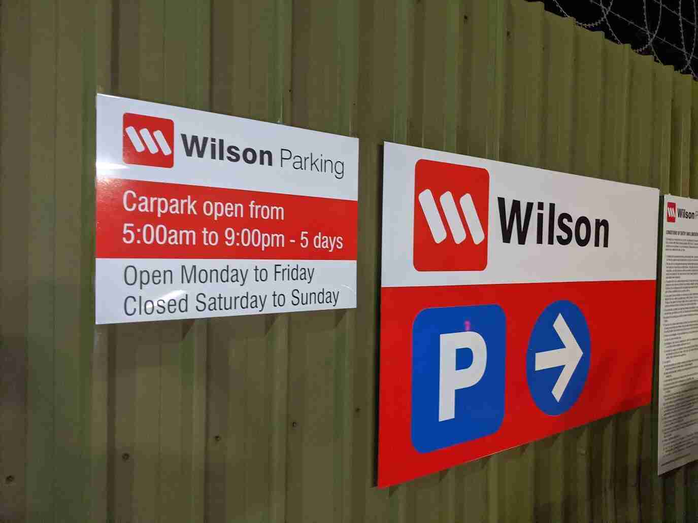 Wilson Parking red and blue directional signage with operating hours
