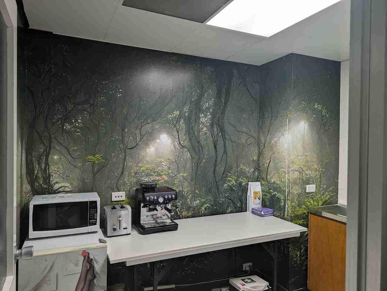Forest-themed wall mural installed behind kitchenette in commercial space