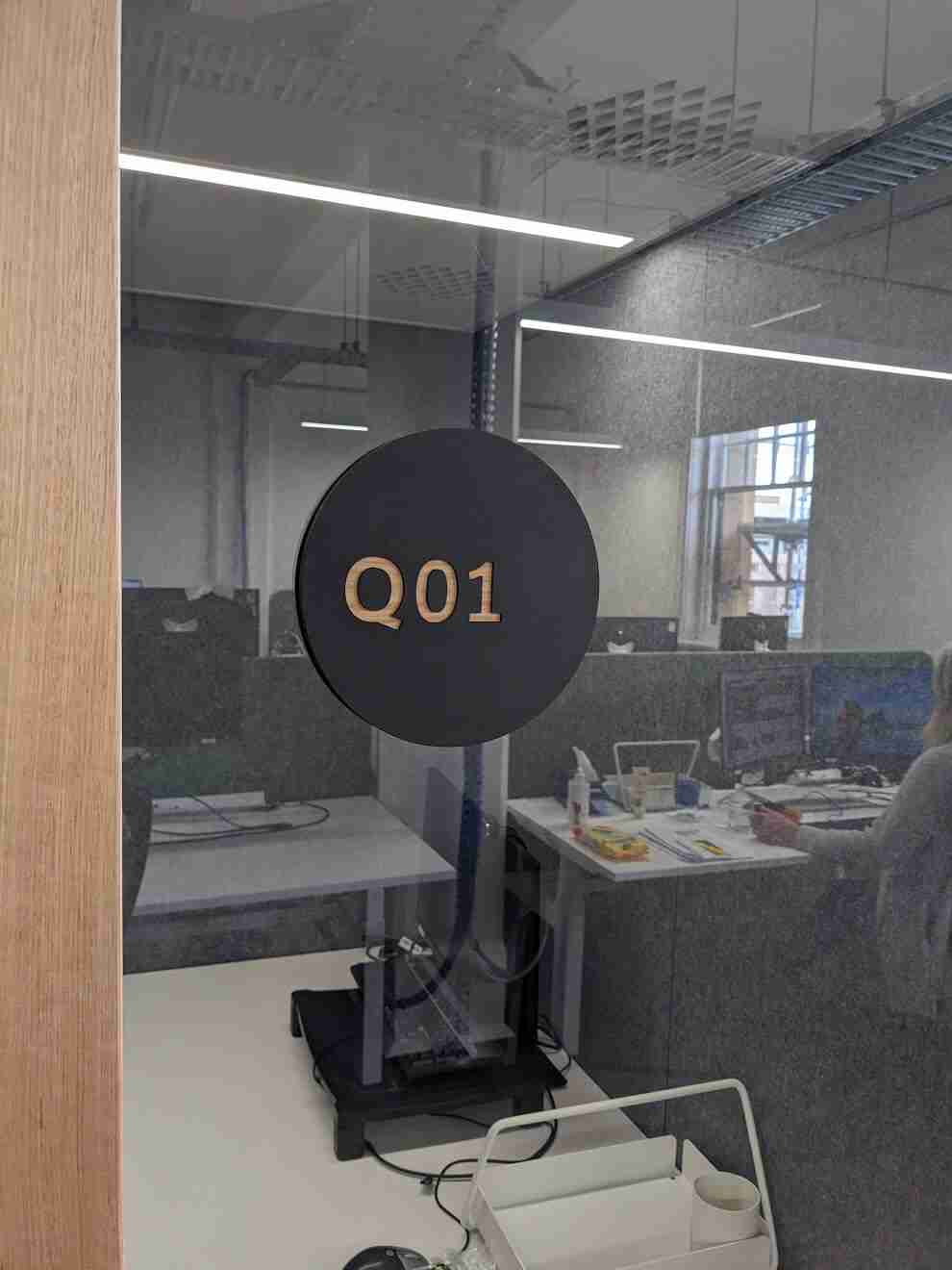 Office glass partition featuring Q01 circular room identification sign