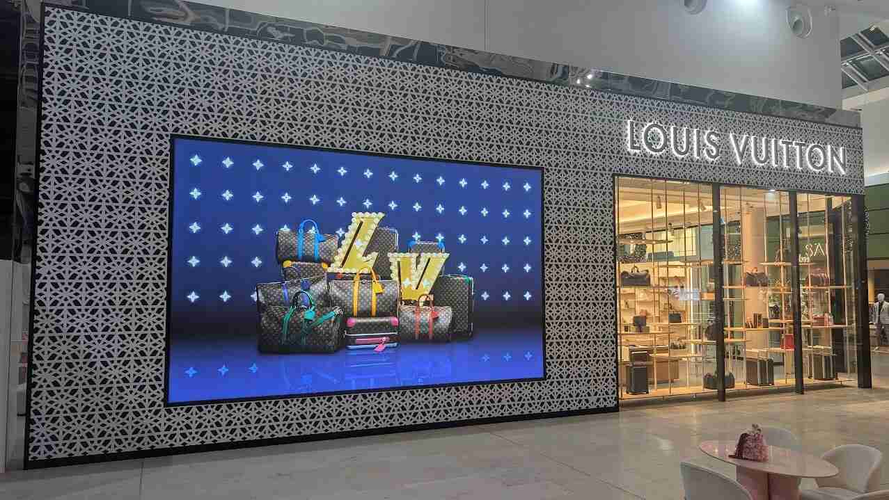 Large-format digital screen mounted within patterned retail wall wrap