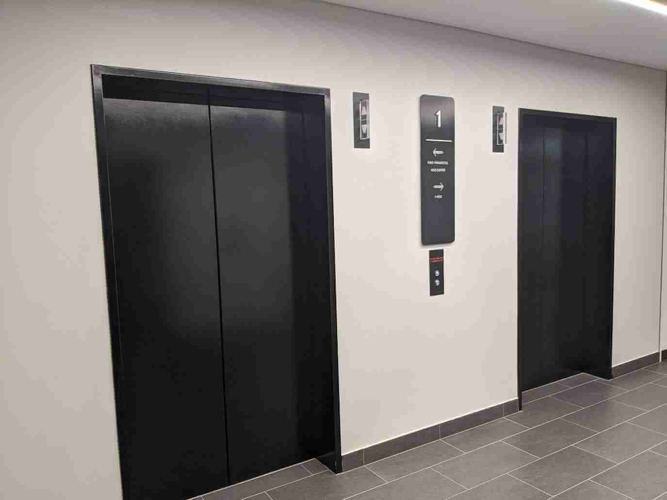 Lift lobby featuring black wall-mounted directional and level signage
