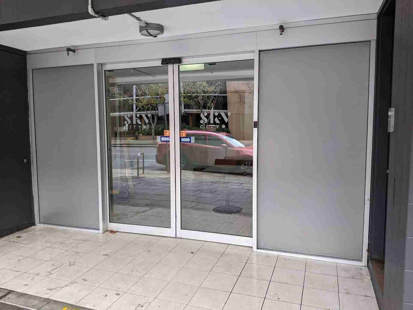 Blank grey shopfront with glass entrance door awaiting signage installation