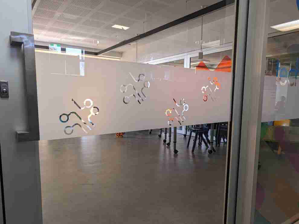 Frosted privacy film with adjoining colourful printed panel in office interior
