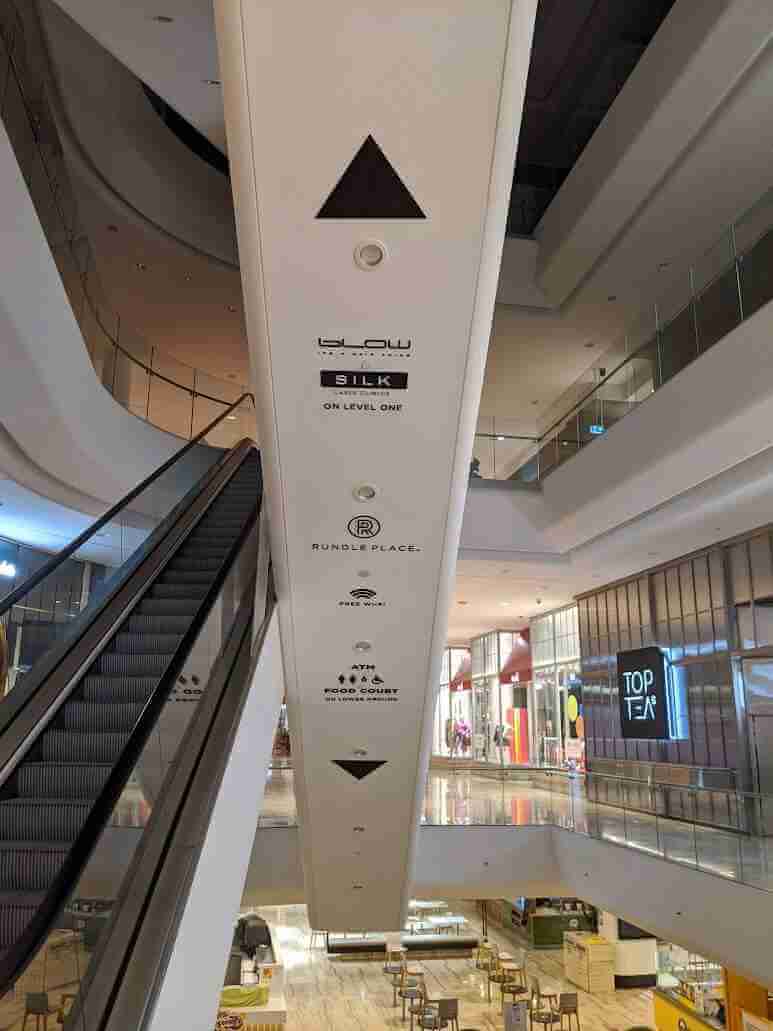Shopping centre directory signage applied to column with tenant listings and icons
