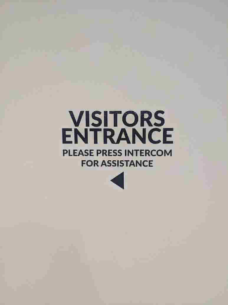 Visitors Entrance wall signage instructing intercom press for assistance