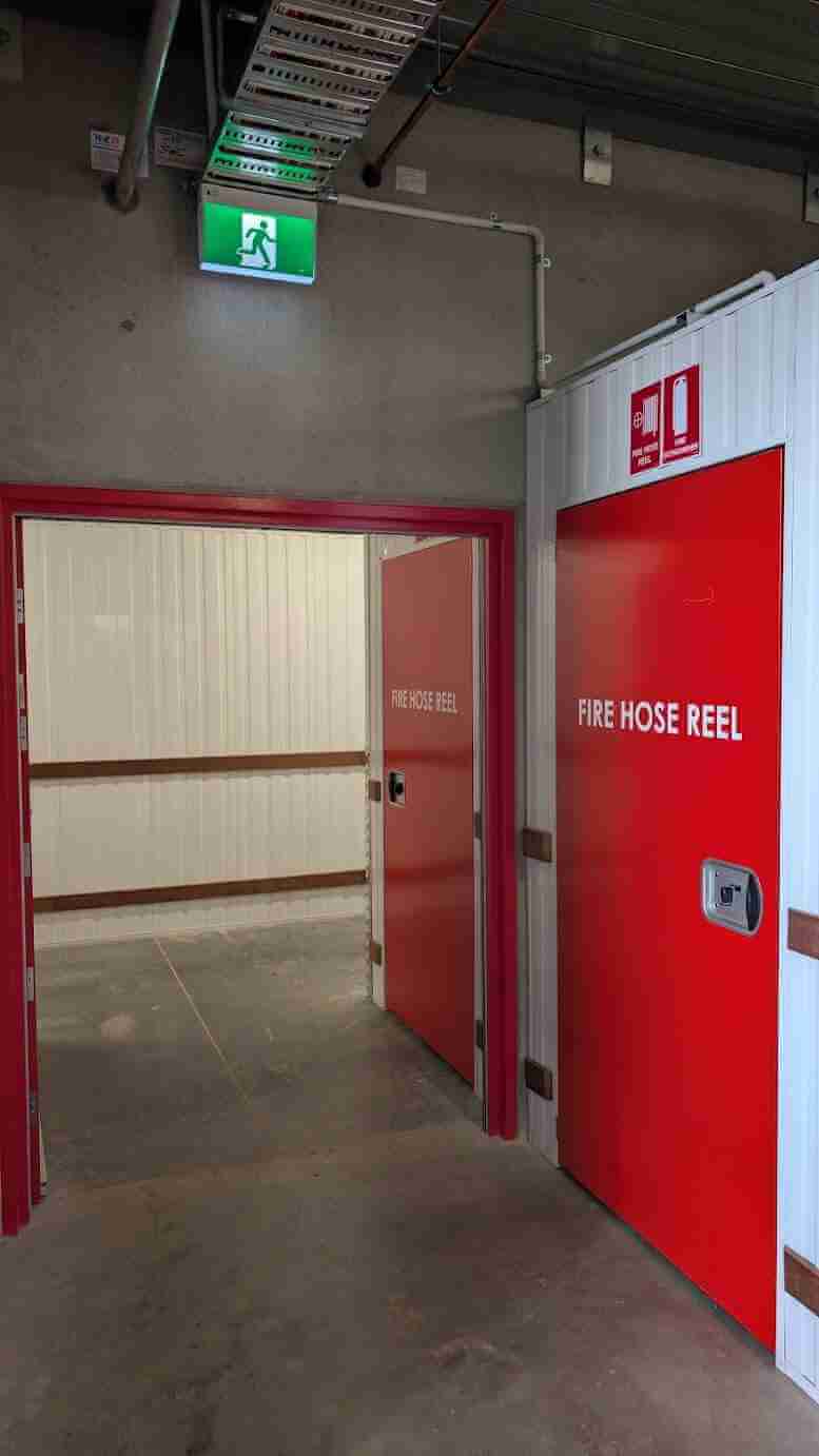 Red fire hose reel door with EXIT signage installed in commercial building