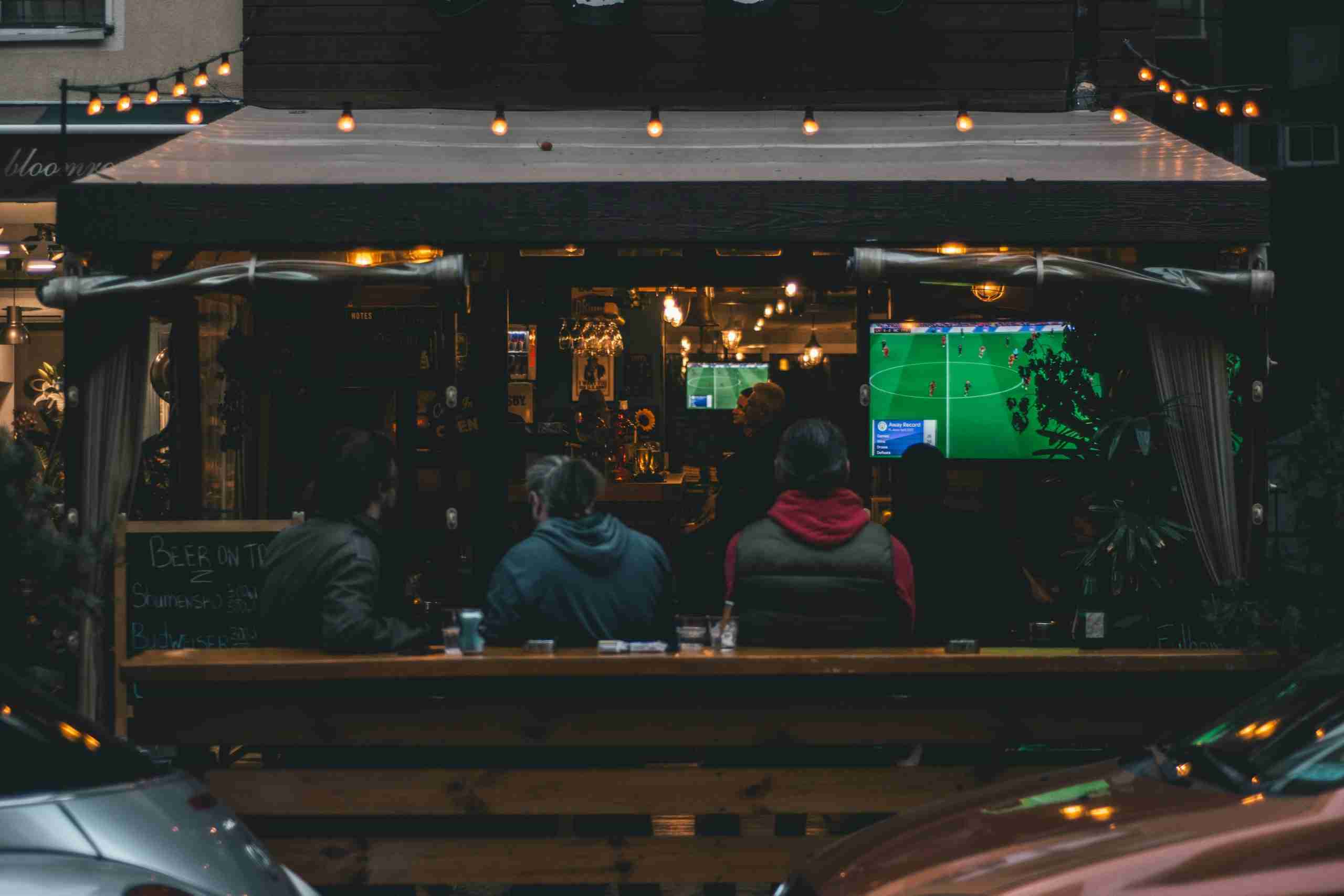 Large digital screen displaying live sports inside a busy bar venue, showing how LED displays are used in hospitality environments